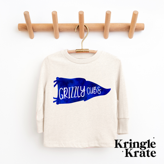 A natural heather-colored long-sleeve t-shirt featuring a bold royal blue pennant flag graphic with the words "Grizzly Cubs" in playful white lettering. The shirt is displayed hanging on a wooden hanger against a white background, showcasing its simple yet spirited design. The t-shirt is a youth size, perfect for young fans, and has a casual, comfortable style ideal for showing school pride.