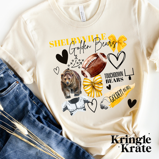 A cream-colored short-sleeve t-shirt featuring a vibrant, collage-style design that celebrates the Shelbyville Golden Bears. The design includes football-themed graphics such as a helmet, shoulder pads, football, foam finger labeled "#1," a whistle, and a football play diagram. Additional playful elements like black hearts and gold and blue bows add to the spirit of the design. The text "Shelbyville Golden Bears" is printed in bold and cursive fonts, with "Touchdown Bears" also featured in the design.