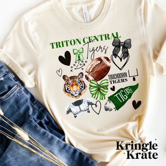 A cream-colored short-sleeve t-shirt featuring a vibrant, collage-style design that celebrates the Triton Central Tigers. The design includes football-themed graphics such as a helmet, shoulder pads, football, foam finger labeled "#1," a whistle, and a football play diagram. Additional playful elements like black hearts and red and blue bows add to the spirit of the design. The text "Triton Central Tigers" is printed in bold and cursive fonts, with "Touchdown Tigers" also featured in the design.